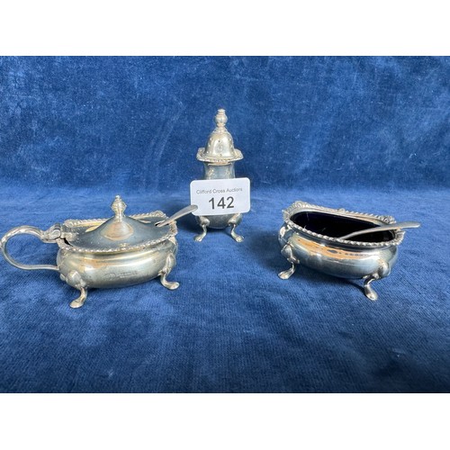 142 - A three-piece cruet set with gadrooned edging, blue glass liners and spoons hallmarked Birmingham