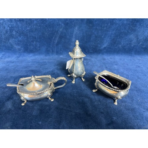 142 - A three-piece cruet set with gadrooned edging, blue glass liners and spoons hallmarked Birmingham