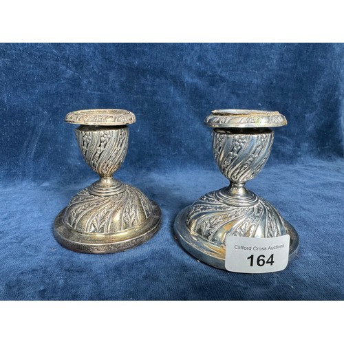 164 - A pair of silver candlesticks with profuse embossed floral and foliage decoration with removable sco... 