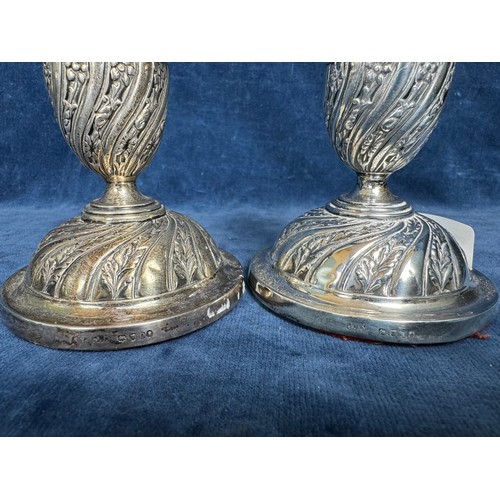 164 - A pair of silver candlesticks with profuse embossed floral and foliage decoration with removable sco... 