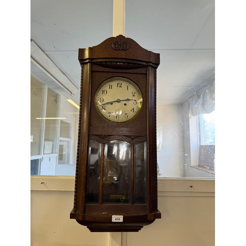 414 - An oak cased wall clock with enamel face and glazed door