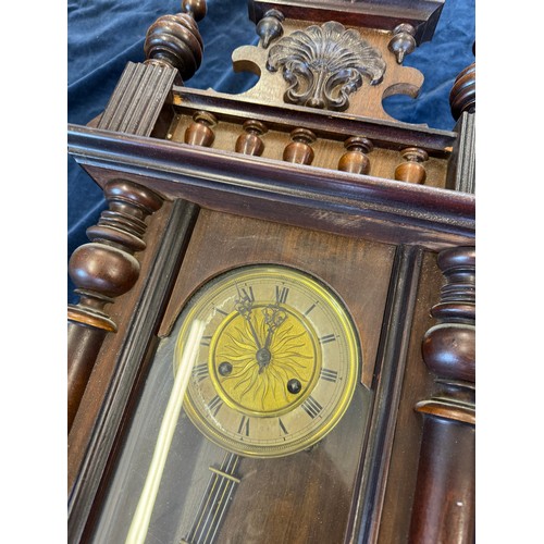 423 - An antique oak cased wall clock with brass dial and pendulum having turned column sides