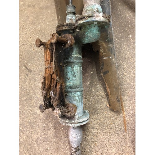 24 - A vintage metal water pump with exposed mechanism  and handle, mounted on wood, with lead pipe.