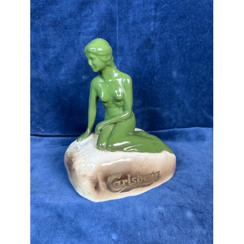 106 - A pottery figure of a green lady seated on rock advertising 'Carlsberg'.