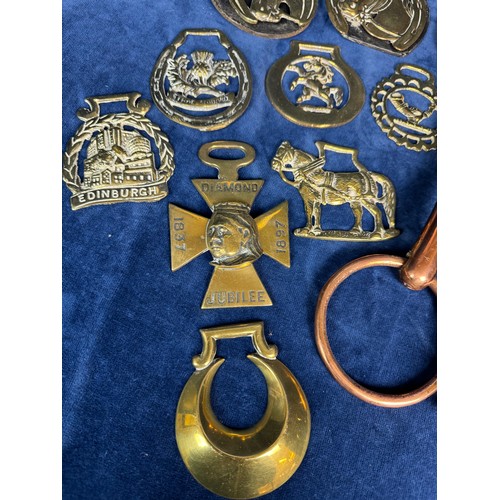 385 - A collection of antique horse brasses and leather straps, together with a copper horse bit.