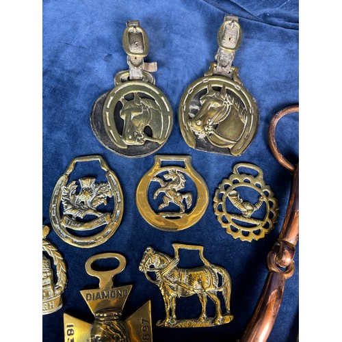 385 - A collection of antique horse brasses and leather straps, together with a copper horse bit.