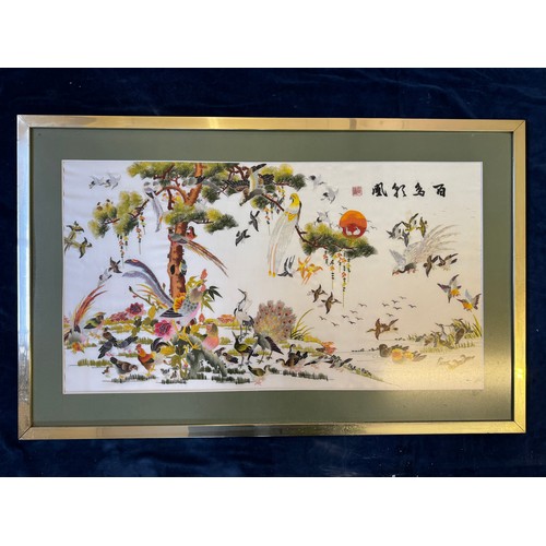 54 - A framed Oriental tapestry depicting exotic birds with tree and pond.