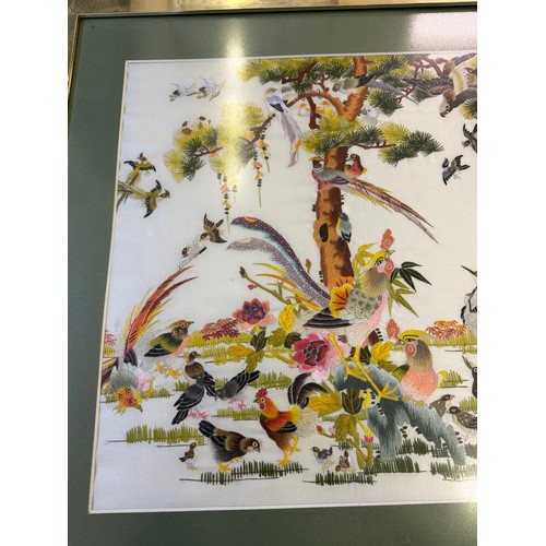 54 - A framed Oriental tapestry depicting exotic birds with tree and pond.