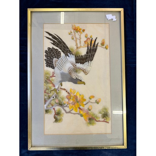 55 - A framed Oriental inspired tapestry depicting 'An eagle taking flight from tree with blossom'.