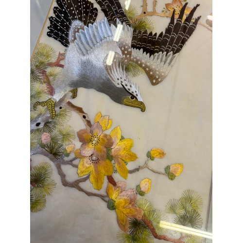 55 - A framed Oriental inspired tapestry depicting 'An eagle taking flight from tree with blossom'.