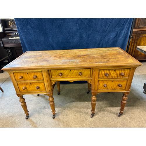 An antique satinwood desk on turned legs with castors, with 2 drawers