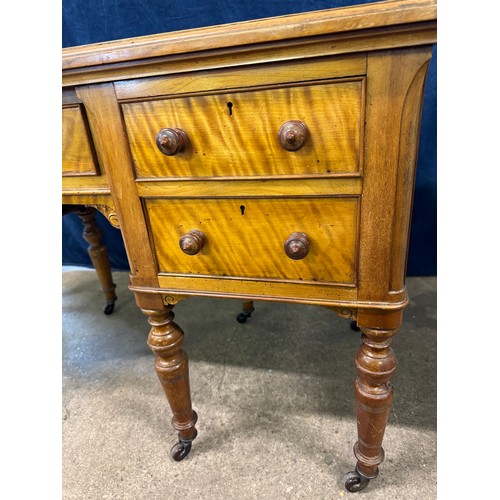 An antique satinwood desk on turned legs with castors, with 2 drawers