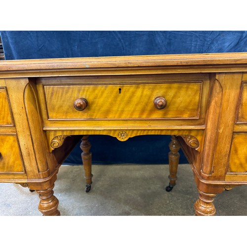 An antique satinwood desk on turned legs with castors, with 2 drawers