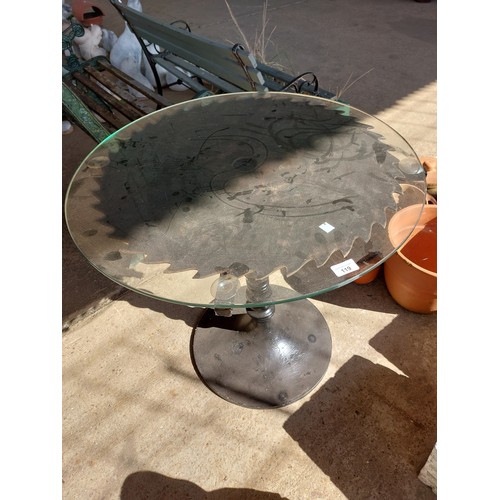 119 - CIRCULAR TABLE WITH SAW BLADE AND GLASS TOP, DIAMETER 71CM APPROXIMATLEY.