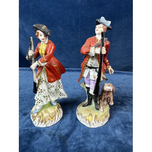 216 - A pair of Dresden porcelain figures depicting a huntsman with rifle and a dog, and a lady holding a ... 