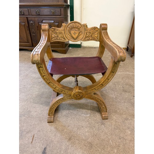 461 - An oak framed carved chair in the style of a savonarola chair, on an 'X' framed base.