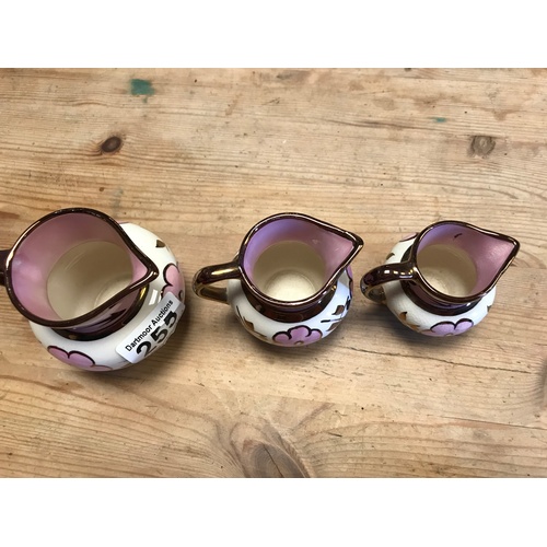 255 - Three graduating lustreware jugs