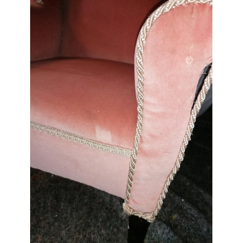 62 - An antique wing back armchair on castors, upholstered in salmon pink Draylon, cream braid piping - s... 