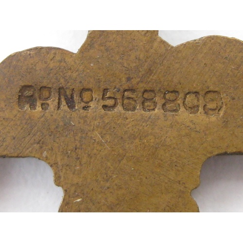 348 - A swastika-shaped metal pendant with plume of feathers in centre and a registration number stamped o... 