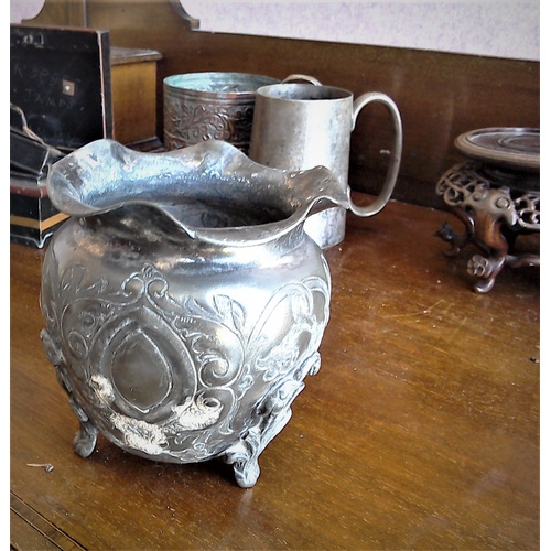 204 - A lot: an antique white metal three-legged pot with ruffled rim, relief and repousse decoration; two... 