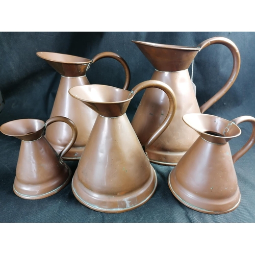 256 - A set of five graduated copper jugs, the bell shaped bodies with loop handle