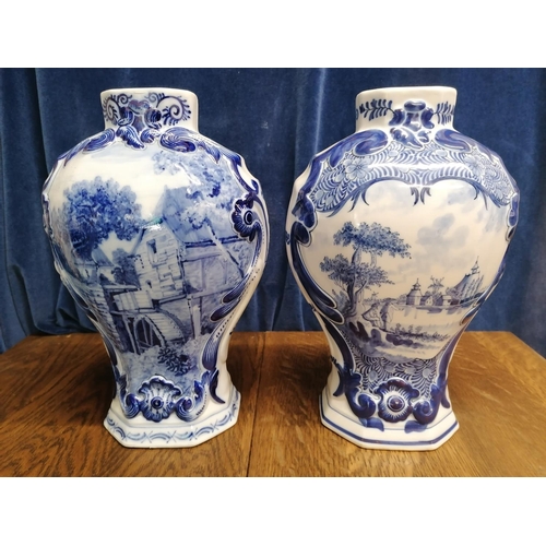 113 - Two Delft blue baluster-shaped chimney vases one decorated with a mill race,the other a river landsc... 