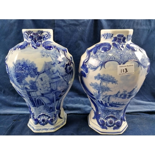113 - Two Delft blue baluster-shaped chimney vases one decorated with a mill race,the other a river landsc... 