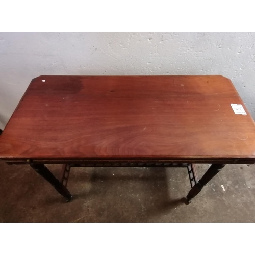 312 - Edwardian mahogany folding games table with turned legs and casters (some attention required).