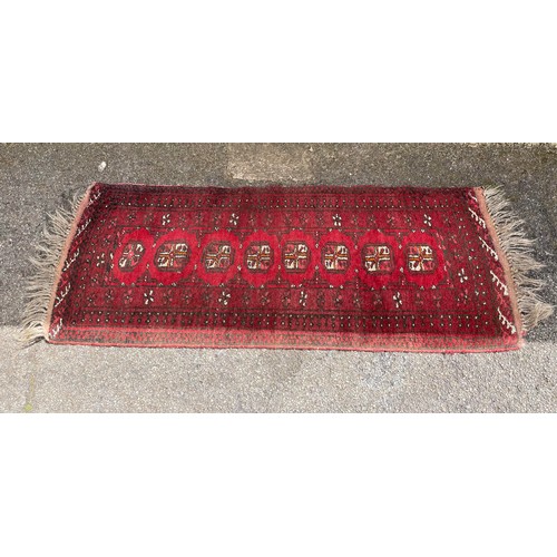 383 - A runner rug - patterned in red. Measures : 134 cm x 50 cm 0- in need of a good clean.