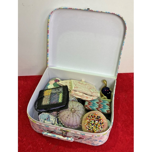 321 - A mini cardboard suitcase containing pin cushions and needle wallets