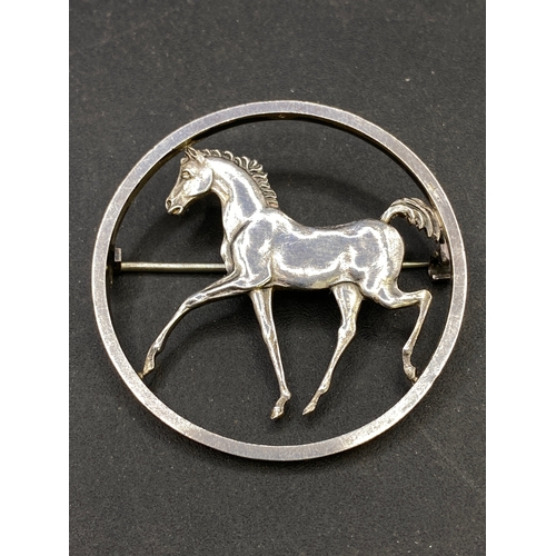 438 - Designer circular silver brooch depicting a prancing horse by George Tarratt