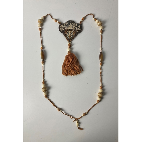 450C - An Art Deco long necklace with carved bone, handmade glass & horn beads
 threaded on silk, & hung wi... 