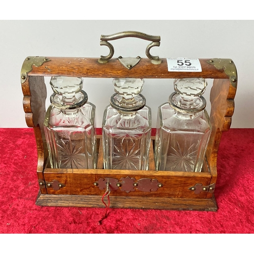 55 - A tantalus with three glass decanters includes the key