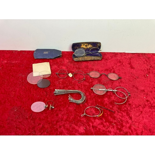 654 - A selection of old spectacle wired frames and a few lenses and a metal spectacle case , one case in ... 