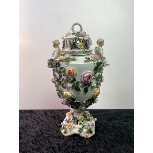 35 - Tall 19th century porcelain lidded urn with cherubs. Heavily decorated with roses. Slight damage to ... 