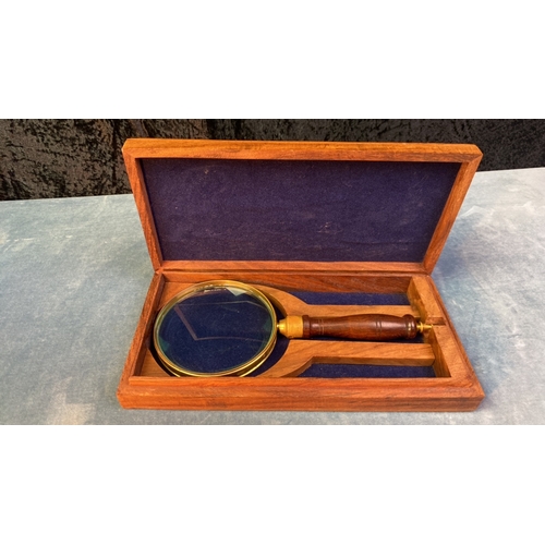 64 - Wooden handled brass rimmed magnifying glass in a wooden case with inlaid brass anchor