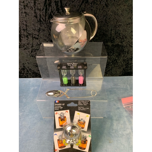 201 - A basket laden with new  tea infusing devices, in original packaging. inc glass teapots and strainer... 