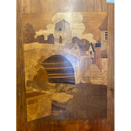 414 - Wooden marquetry scene of a town with river / canal, approx 44.5cm x 34.5cm (chip to top of board)