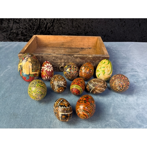 354 - A collection of 12 Oriental and Indonesian style hand painted eggs in a pretty wooden drawer