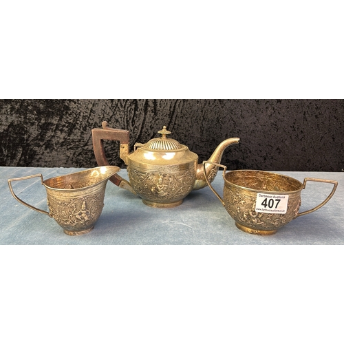 407 - Siamese influence repoussé style white metal tea set comprising teapot, sugar bowl and milk jug