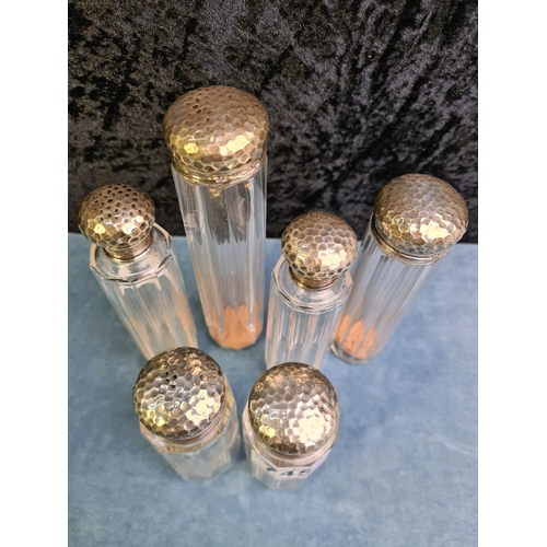 745 - Six matching silver topped glass dressing table bottles of varying size with hammered design lids, a... 