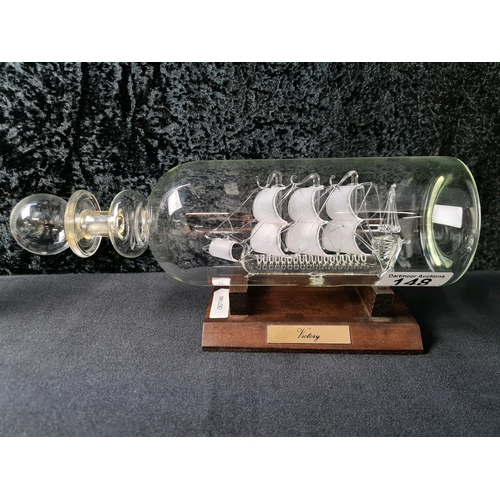 148 - Two exquisite glass ships in bottles on wooden stands featuring 'Victory' and 'Voyager'