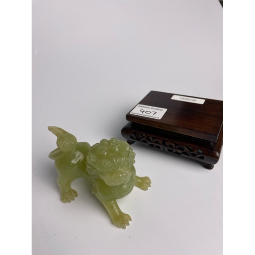 407 - Jade colour Chinese dog of foo on a wooden stand, dog measures 6.5cm tall