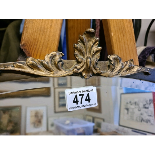 474 - Oval bevel edged mirror with gilt motif. Measuring approx 57cm high and 78cm wide (at widest points)... 