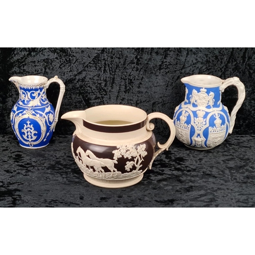 146 - Pair of antique Cobridge bas-relief blue and white jugs (smallest one has repair to lip) and and a b... 