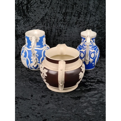 146 - Pair of antique Cobridge bas-relief blue and white jugs (smallest one has repair to lip) and and a b... 