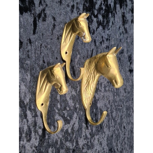 111 - Pair of brass candle holders, candle wall scones and three charming horse head brass hooks.