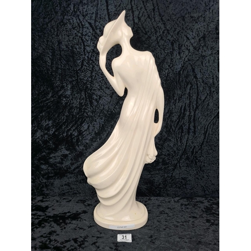31 - Tall, white glazed ceramic figurine of a woman wearing a flowing dress and holding her hat. Approx H... 