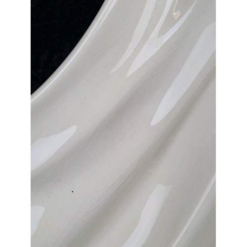 31 - Tall, white glazed ceramic figurine of a woman wearing a flowing dress and holding her hat. Approx H... 