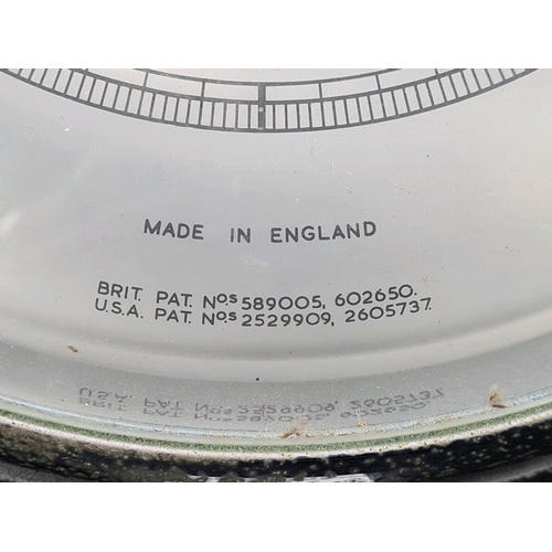 54 - Aneroid barometer with a silvered dial, a brass bezel, and housed in a carved wooden case. Approx Di... 